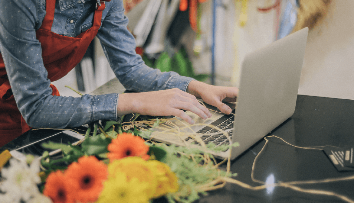 Female florist taking orders using laptop